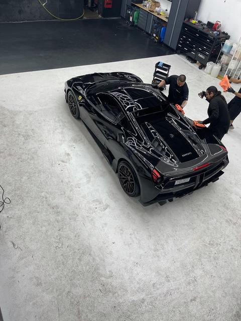 Team detailing a black Ferrari in the 68 Auto Film bay