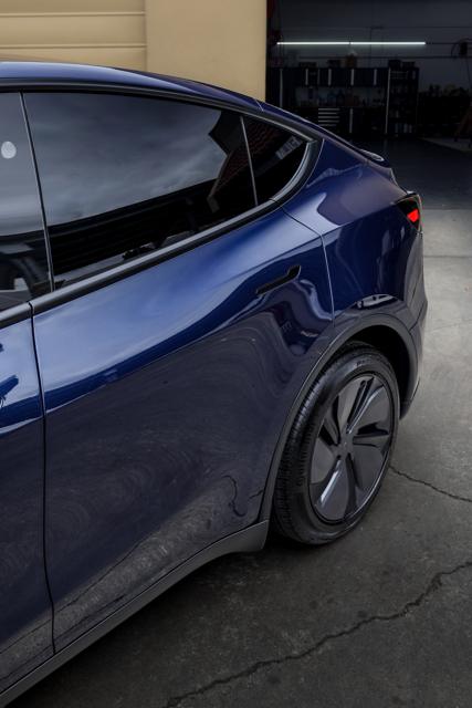 Dark blue Tesla Model Y side with tinted rear windows