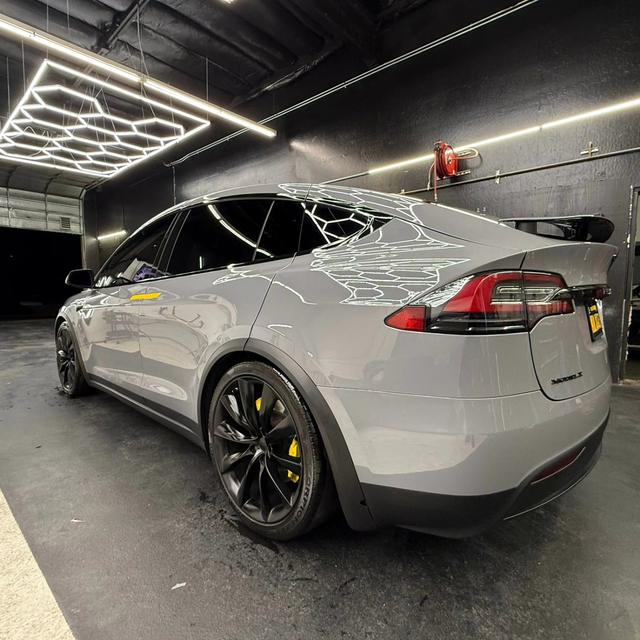 Grey Tesla Model X under hex lighting in the 68 Auto Film bay