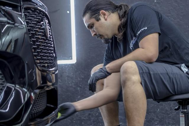 68 Auto Film technician detailing a black car's front end