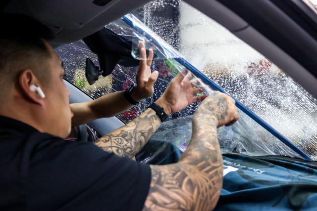 Installer smoothing windshield film with a squeegee at 68 Auto Film