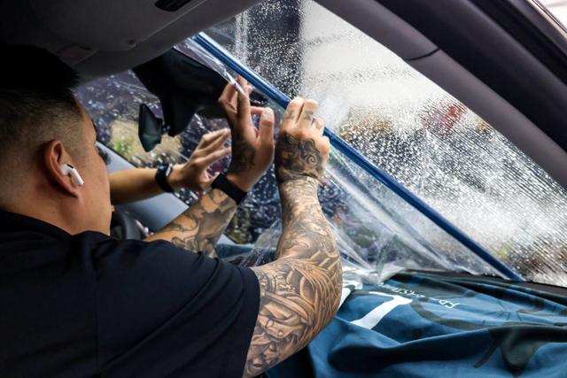 Two installers applying clear film to a windshield at 68 Auto Film