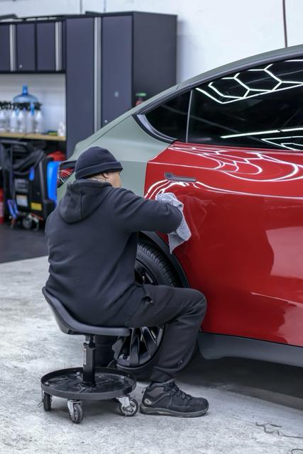 Technician working on the door of a red Tesla